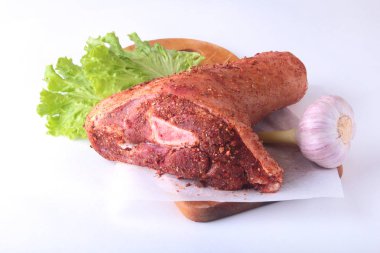 Çiğ domuz knuckle, sarımsak, baharat ve marul yaprakları bir kesme tahtası üzerinde. Seçici odak. Hazır yemek pişirmek için.