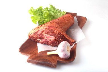 Çiğ domuz knuckle, sarımsak, baharat ve marul yaprakları bir kesme tahtası üzerinde. Seçici odak. Hazır yemek pişirmek için.