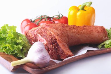 Çiğ domuz knuckle ve sebze, sarımsak, domates, dolmalık biber. baharat ve marul yaprakları bir kesme tahtası üzerinde. Seçici odak. Hazır yemek pişirmek için.