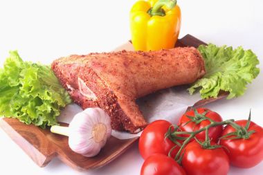 Çiğ domuz knuckle ve sebze, sarımsak, domates, dolmalık biber. baharat ve marul yaprakları bir kesme tahtası üzerinde. Seçici odak. Hazır yemek pişirmek için.