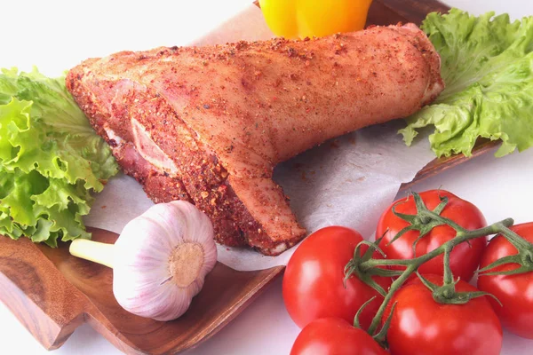 Çiğ domuz knuckle ve sebze, sarımsak, domates, dolmalık biber. baharat ve marul yaprakları bir kesme tahtası üzerinde. Seçici odak. Hazır yemek pişirmek için.