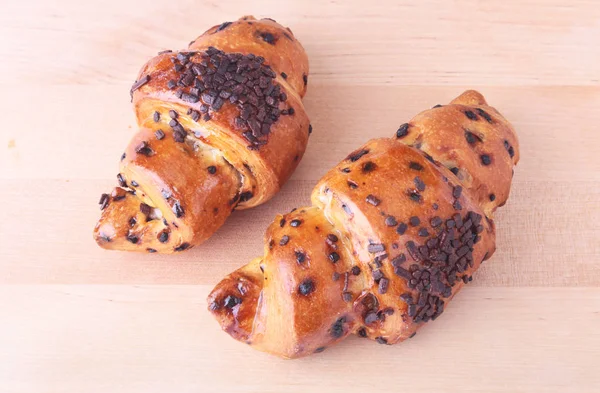 Crispy fresh croissant isolated on wooden background, selective focus. — Stock Photo, Image