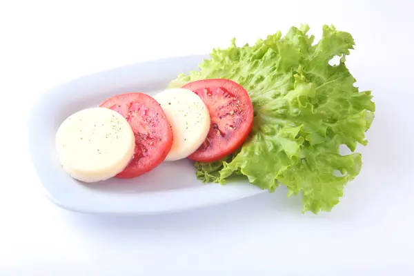 Порция моцареллы с помидорами, листом салата и бальзамическим соусом на белой тарелке. селективный фокус крупным планом . — стоковое фото