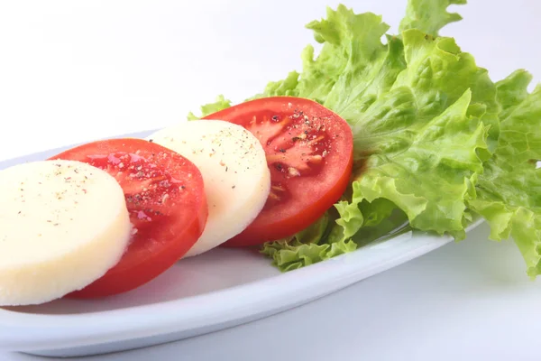Część Mozzarella z pomidorami, liść sałaty i balsamicznym na białym talerzu. Selektywny fokus bliska strzał. — Zdjęcie stockowe