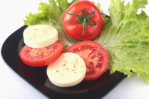 Порция моцареллы с помидорами, листом салата и бальзамическим соусом на черной тарелке. селективный фокус крупным планом . — стоковое фото