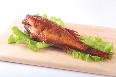 Füme balık ve beyaz arka plan üzerinde izole tahta kesme tahta üzerinde yeşil marul yaprakları limon.