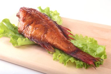 Füme balık ve beyaz arka plan üzerinde izole tahta kesme tahta üzerinde yeşil marul yaprakları limon.