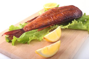 Füme balık ve beyaz arka plan üzerinde izole tahta kesme tahta üzerinde yeşil marul yaprakları limon.