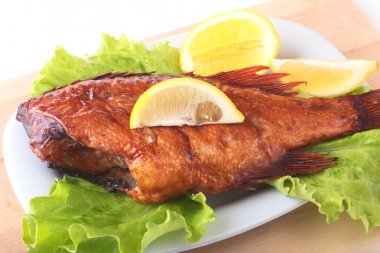 Füme balık ve beyaz arka plan üzerinde izole tahta kesme tahta üzerinde yeşil marul yaprakları limon.