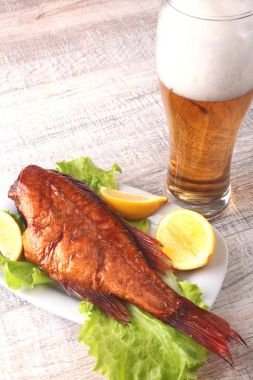 Beyaz arka plan üzerinde izole bira ile balık ve limon yeşil marul yaprakları ahşap kesme tahtası ve cam üzerinde füme.