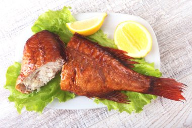 Füme balık ve beyaz arka plan üzerinde izole tahta kesme tahta üzerinde yeşil marul yaprakları limon.