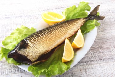 Mackerele ve beyaz arka plan üzerinde izole tahta kesme tahta üzerinde yeşil marul yaprakları limon füme.