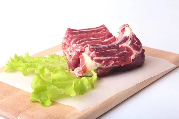 Rått nötkött kanter och salladsblad på trä skrivbord isolerade på vit bakgrund från ovan och kopiera utrymme. redo för matlagning — Stockfoto