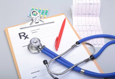 RX reçeteli, stetoskop ve beyaz zemin üzerine kalem.