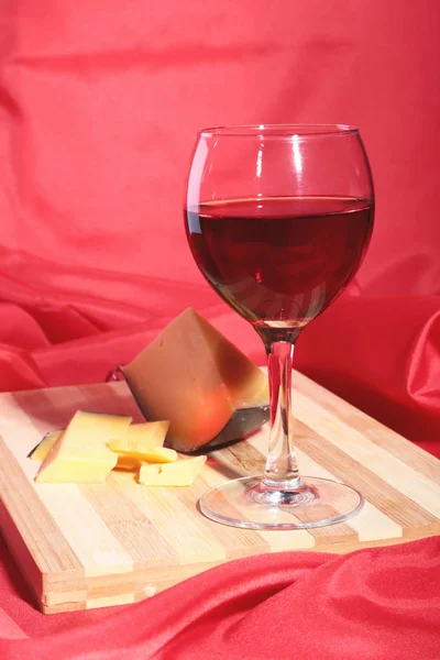 Butelki i kieliszki z czerwonych winogron i Sery żółte na drewnianym stole. — Zdjęcie stockowe