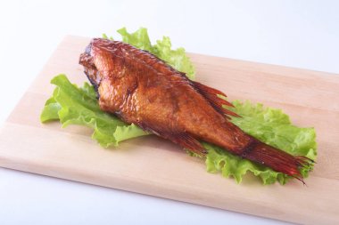 Füme balık ve beyaz arka plan üzerinde izole tahta kesme tahta üzerinde yeşil marul yaprakları limon.