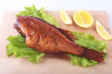 Füme balık ve beyaz arka plan üzerinde izole tahta kesme tahta üzerinde yeşil marul yaprakları limon.