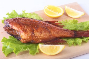 Füme balık ve beyaz arka plan üzerinde izole tahta kesme tahta üzerinde yeşil marul yaprakları limon.