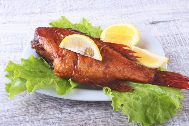 Füme balık ve beyaz arka plan üzerinde izole tahta kesme tahta üzerinde yeşil marul yaprakları limon.