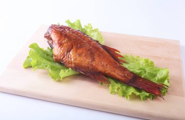 Füme balık ve beyaz arka plan üzerinde izole tahta kesme tahta üzerinde yeşil marul yaprakları limon.