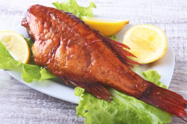 Füme balık ve beyaz arka plan üzerinde izole tahta kesme tahta üzerinde yeşil marul yaprakları limon.