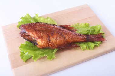 Füme balık ve beyaz arka plan üzerinde izole tahta kesme tahta üzerinde yeşil marul yaprakları limon.