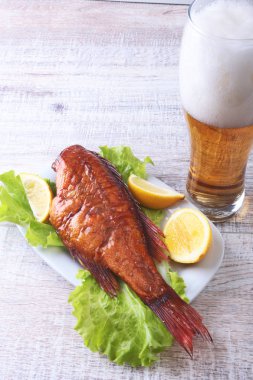 Beyaz arka plan üzerinde izole bira ile balık ve limon yeşil marul yaprakları ahşap kesme tahtası ve cam üzerinde füme.