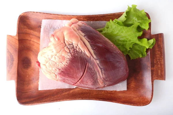 Ham sığır eti yaprak ahşap masa yukarıdan beyaz arka plan ve kopya alanı izole kalp ve marul. hazır yemek pişirmek için.