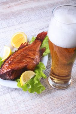 Beyaz arka plan üzerinde izole bira ile balık ve limon yeşil marul yaprakları ahşap kesme tahtası ve cam üzerinde füme.