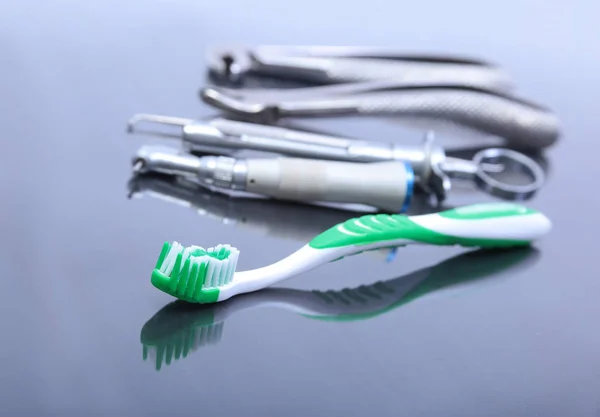 Cepillo dental con herramientas de dentista sobre fondo espejo . — Foto de Stock