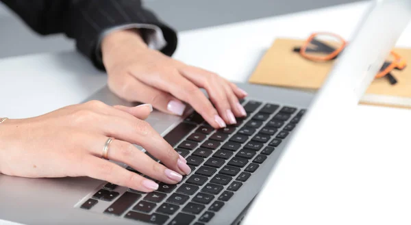Ділова жінка працює на ноутбуці, сидячи за столом в офісі . — стокове фото