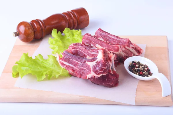 Bords de boeuf cru, feuille de laitue, moulin à poivre et épices sur un bureau en bois isolé sur fond blanc d'en haut et espace de copie. prêt pour la cuisson . — Photo