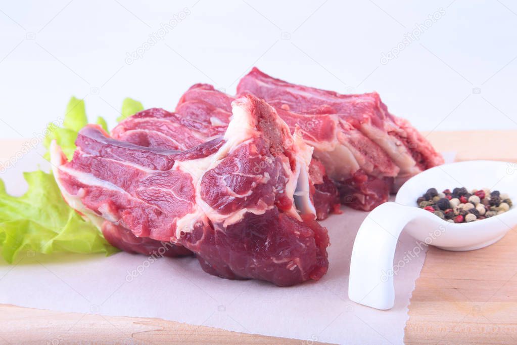 Raw beef edges, lettuce leaf and spices on wooden desk isolated on white background from above and copy space. ready for cooking.