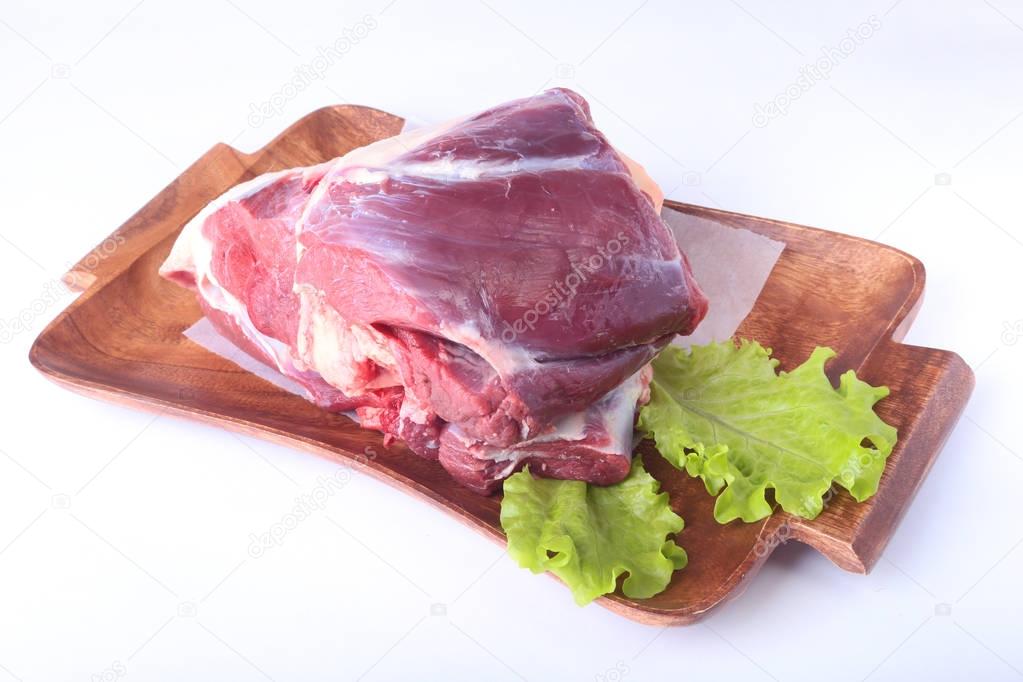 Raw beef shanks and lettuce leaf on wooden desk isolated on white background from above and copy space. ready for cooking.