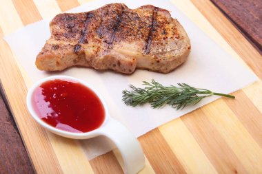 ızgara domuz eti ile kızılcık sosu ahşap tahta üzerinde plaka üzerinde