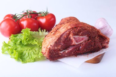 Çiğ domuz knuckle ve sebze, sarımsak, domates baharat ve marul yaprakları bir kesme tahtası üzerinde. Seçici odak. Hazır yemek pişirmek için.