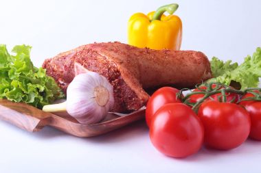 Çiğ domuz knuckle ve sebze, sarımsak, domates, dolmalık biber. baharat ve marul yaprakları bir kesme tahtası üzerinde. Seçici odak. Hazır yemek pişirmek için.