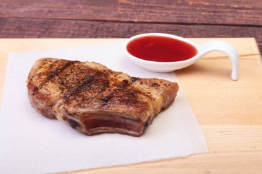 ızgara domuz eti ile kızılcık sosu ahşap tahta üzerinde plaka üzerinde