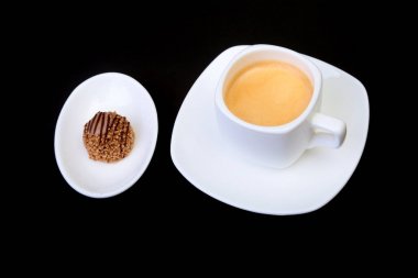 Klasik espresso kahve ve pralin siyah arka plan üzerine beyaz fincan.
