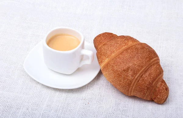 Croissants frescos caseros crujientes y taza de café expreso sobre un fondo blanco, desayuno por la mañana, enfoque selectivo — Foto de Stock