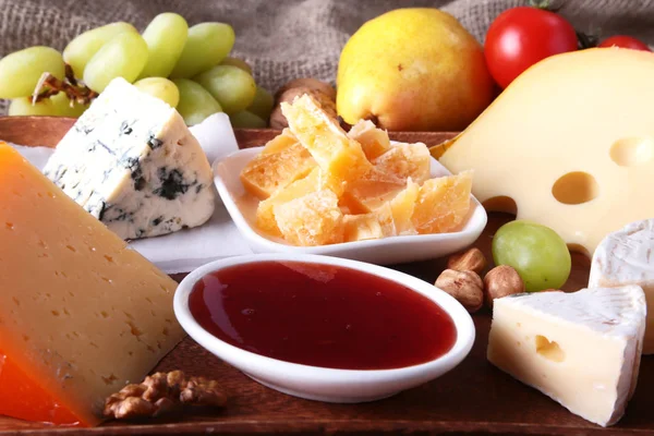 Assortiment van kaas met fruit, druiven en noten op een houten dienblad. — Stockfoto