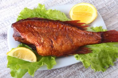 Füme balık ve beyaz arka plan üzerinde izole tahta kesme tahta üzerinde yeşil marul yaprakları limon.