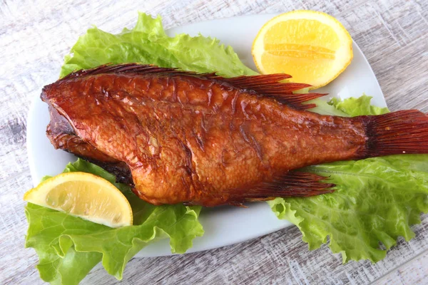 Füme balık ve beyaz arka plan üzerinde izole tahta kesme tahta üzerinde yeşil marul yaprakları limon.