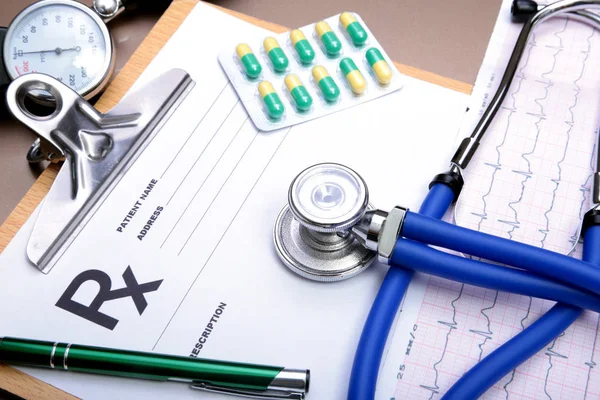 RX prescripción, corazón rojo, pastillas, medidor de presión arterial y un estetoscopio en la mesa . — Foto de Stock