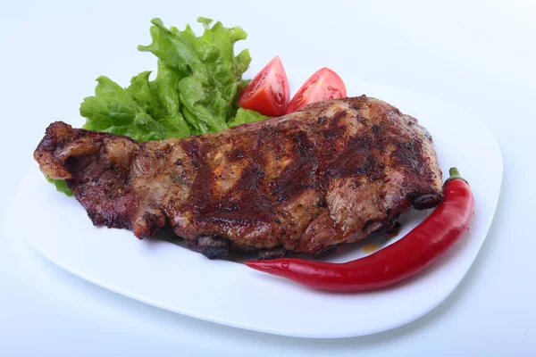 Costeletas de porco na grelha e pimenta com tomate, folhas de alface no prato branco — Fotografia de Stock
