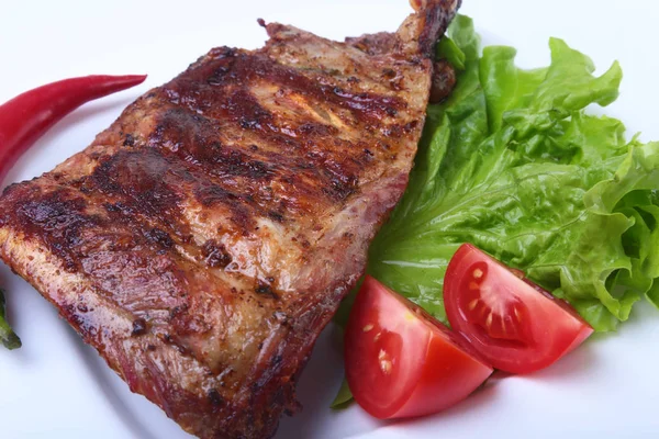 Costillas de cerdo a la parrilla y chile con tomate, hojas de lechuga en plato blanco — Foto de Stock