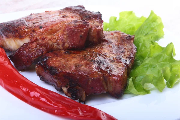 Bistecca di carne alla griglia e peperoncino con pomodoro, foglie di lattuga su piatto bianco . — Foto Stock