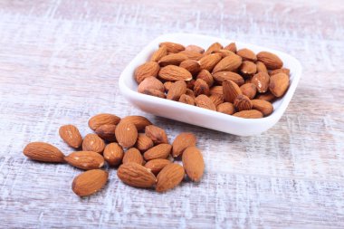 ahşap arka plan üzerinde beyaz kase fındık badem. Seçici odak.