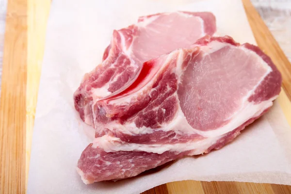 Çiğ domuz pirzolası, kesme tahtası üzerinde baharat. Hazır yemek pişirmek için.