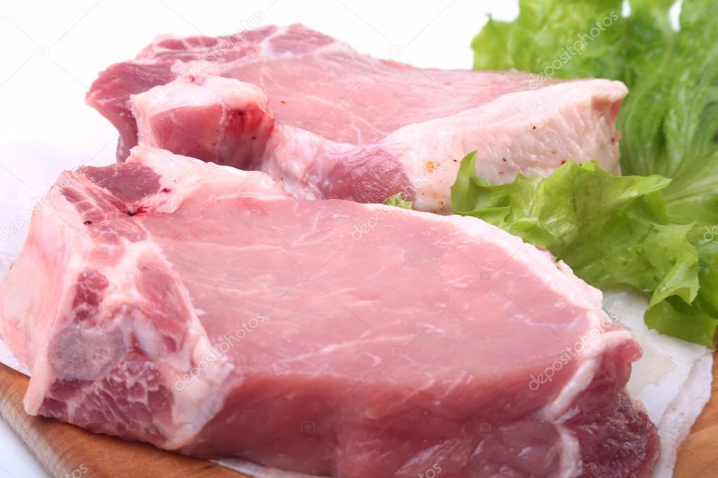 Raw pork chops with herbs and spices on cutting board. Ready for cooking.